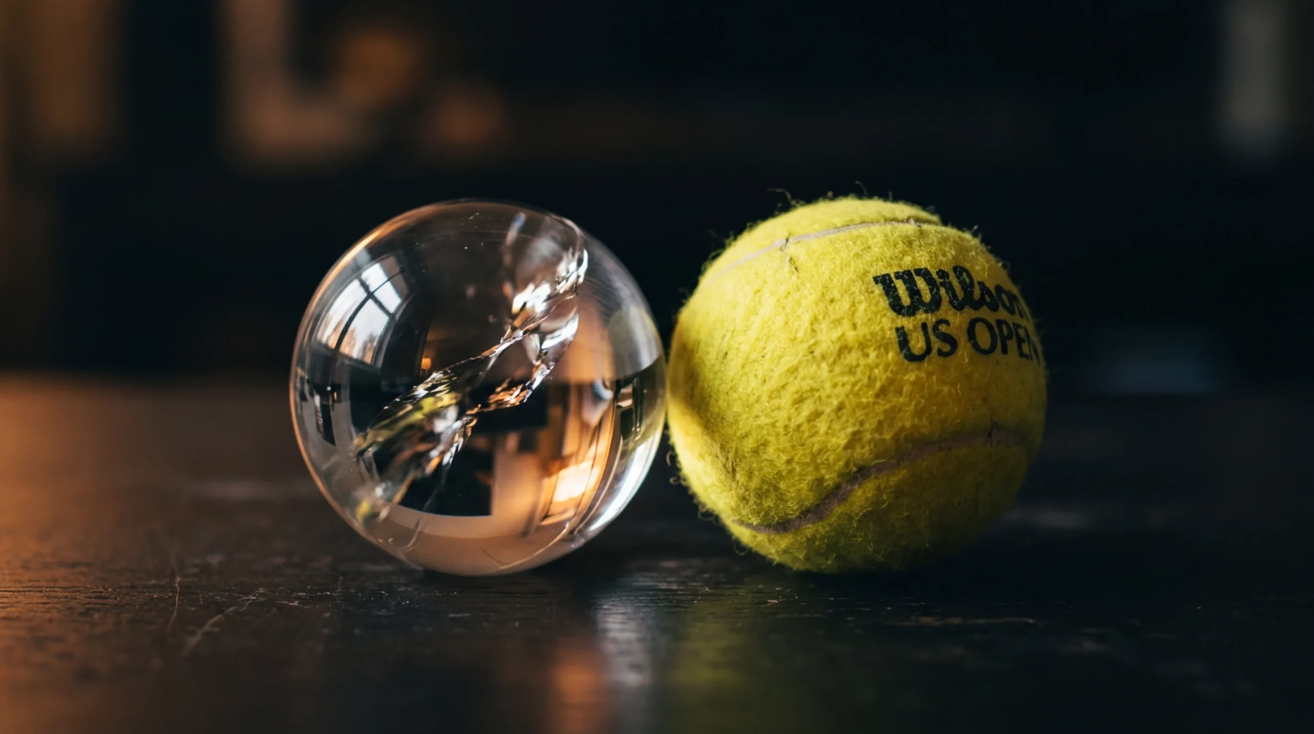Bola de cristal ao lado de uma bola de ténis sobre uma mesa